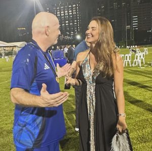 Michelle Ramalho, presidente da FPF, conversa com o presidente da Fifa, Gianni Infantino, em um campo de futebol iluminado à noite, após a escolha do Brasil como sede da Copa do Mundo Feminina de 2027.