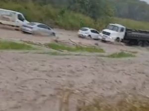 Trecho da rodovia federal BR-101 tomado pela água após transbordamento de manancial, com veículos parados no congestionamento.